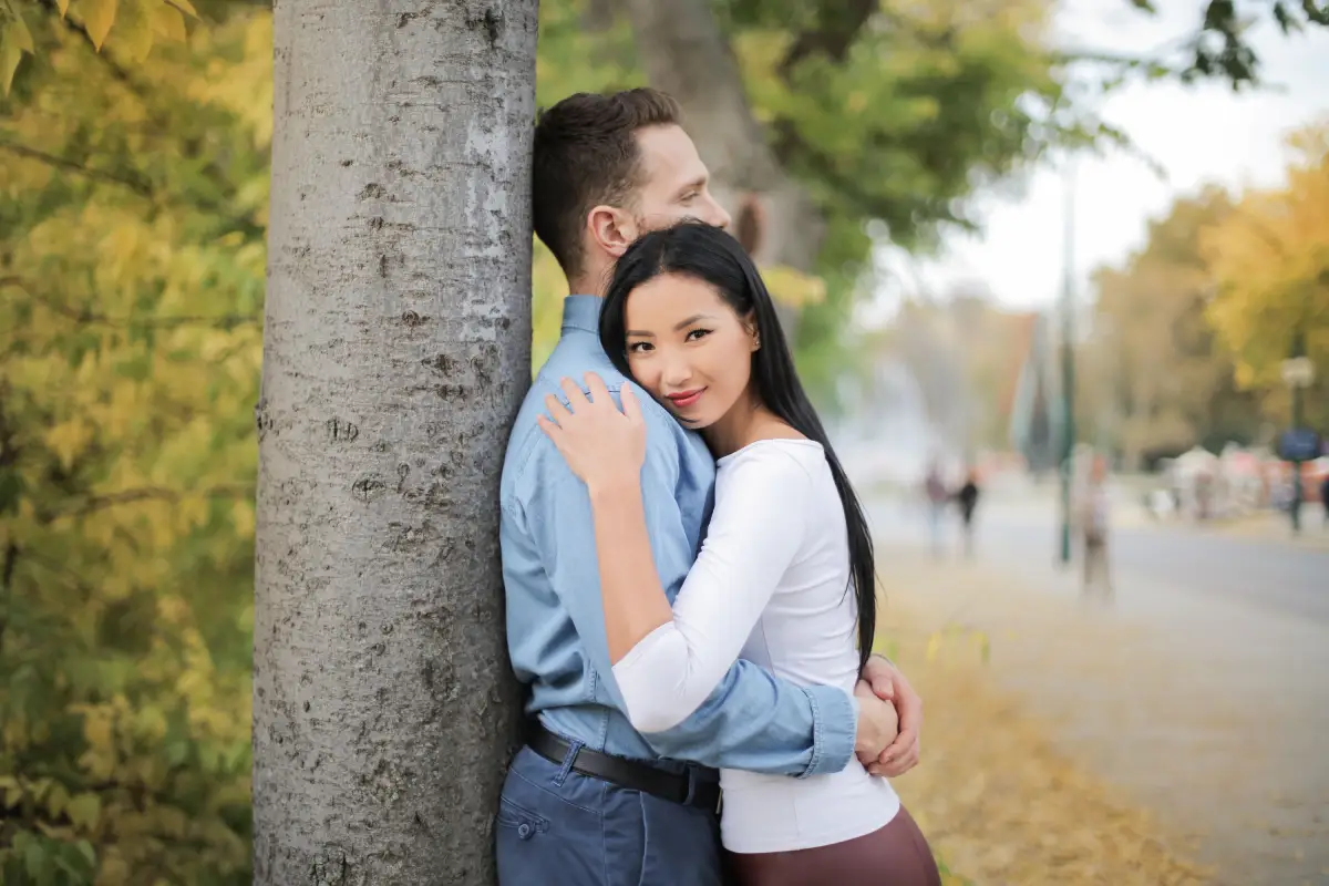 couple hugging and leaning against a tree